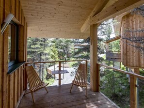 A wooden deck with two wooden chairs and a table, overlooking a forested area. - #23 mir IR-Sauna und Sprudelbad Innen by Interhome (Turracher Höhe)