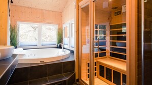 A modern bathroom with a freestanding bathtub, a glass-enclosed sauna, and a window providing natural light. - #23 mir IR-Sauna und Sprudelbad Innen by Interhome (Turracher Höhe)