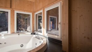 A modern bathroom with a large freestanding bathtub, wooden walls, and large windows. - # 25 mit Sauna und Sprudelbad innen by Interhome (Turracher Höhe)