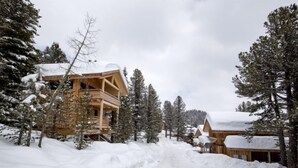 A wooden lodge with a balcony, surrounded by snow-covered trees and a snowy path. - # 25 mit Sauna und Sprudelbad innen by Interhome (Turracher Höhe)