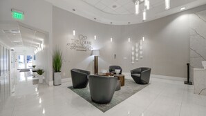 A modern lobby with a reception desk, seating area, and a wall with a heart-shaped design. - The Club- RE Rentals (Miami)