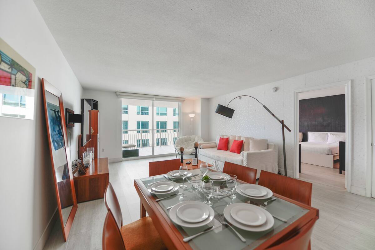 Uma sala de estar moderna com área de jantar posta para quatro pessoas.