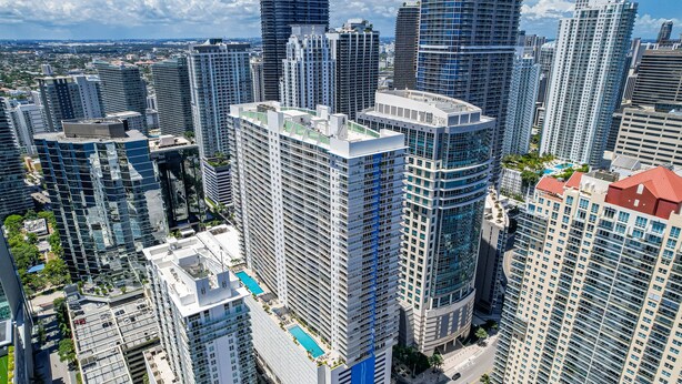 A high-rise building with multiple floors, a rooftop pool, and surrounding high-rise buildings. - The Club- RE Rentals (Miami)
