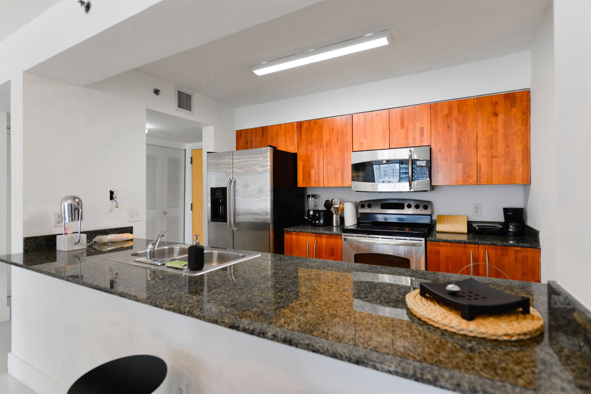 Una cocina moderna con encimeras de granito, electrodomésticos de acero inoxidable y armarios de madera.