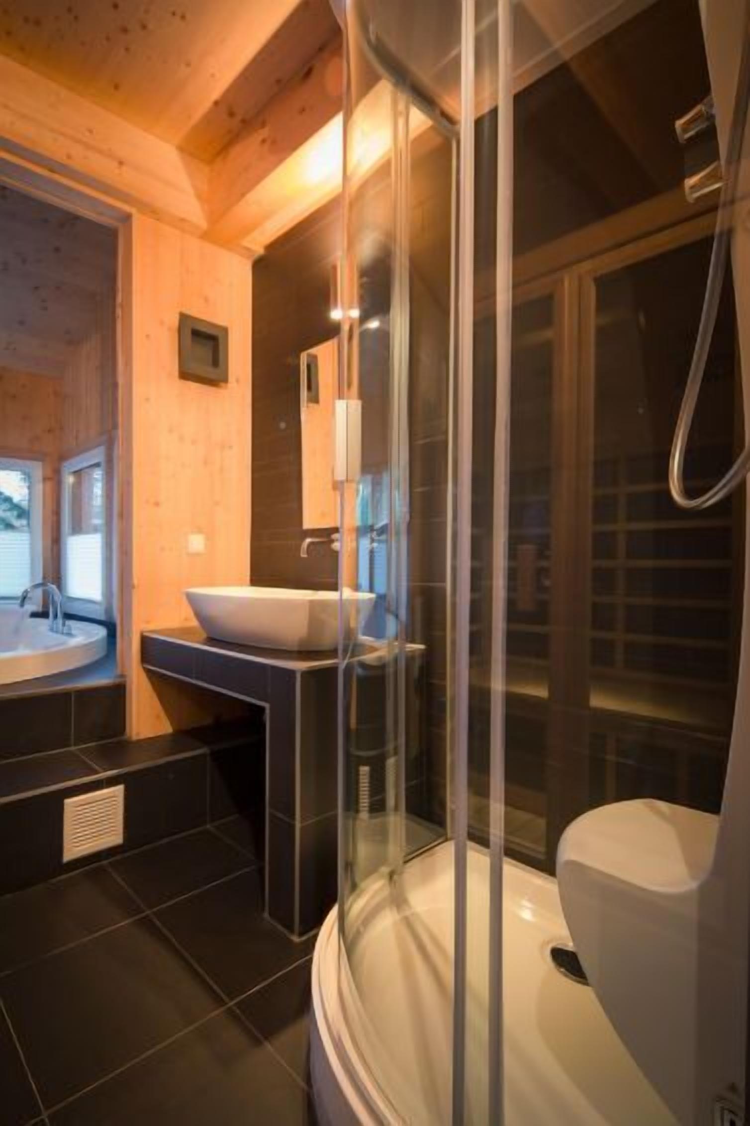 Een moderne badkamer met een vrijstaand bad, een apart toilet en een douchecabine met glazen wanden.