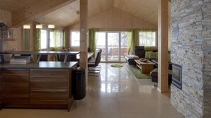 A spacious living area with a wooden ceiling, a stone accent wall, and a dining area with a kitchen counter.