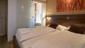 A bedroom with a large bed, a wooden headboard, and a painting on the wall.