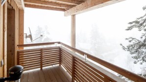 A wooden balcony with a view of snow-covered trees.