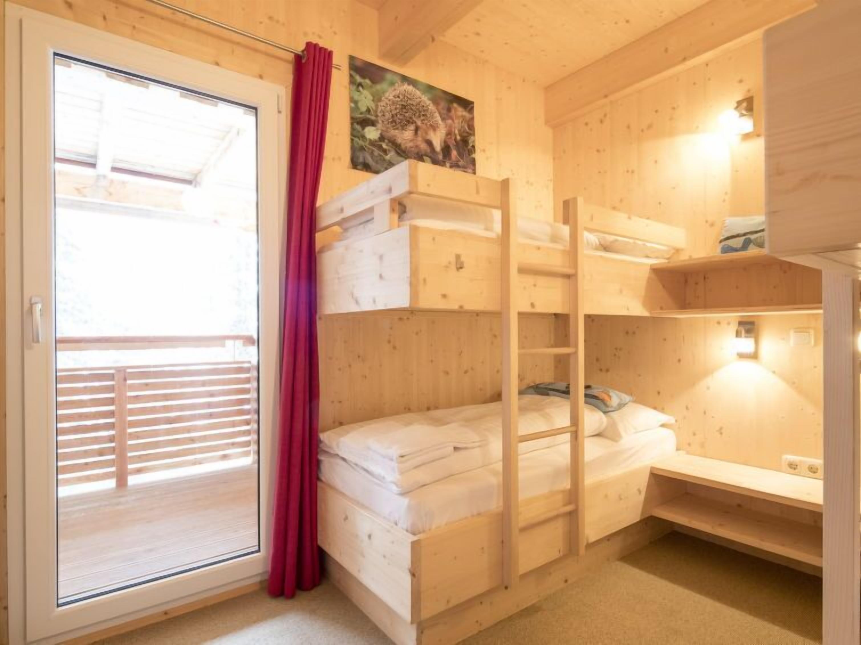 Een houten chalet met stapelbedden, een schuifdeur en een schilderij aan de muur.