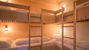 Quarto com beliches, paredes de madeira e luminária à esquerda.