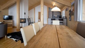 Un vaste espace de vie comprenant une table à manger en bois, un téléviseur et une cheminée.