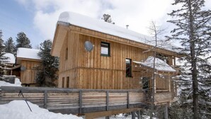Une cabane en bois dotée d’un balcon, entourée d’arbres couverts de neige.