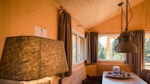A cozy cabin interior with a wooden dining table, a bench, and a large lamp.