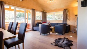 A wooden interior with a dining area, sofas, and a fur rug.