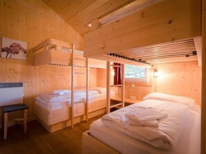 Una cabaña de madera con literas, una mesita y un ventanal con cortinas.