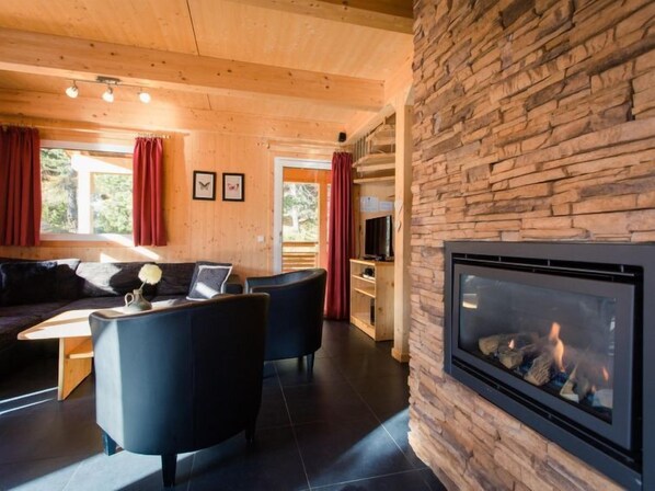 A cozy living room with a stone fireplace, wooden ceiling, and a comfortable sofa.