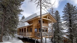 Una cabaña de madera con balcón, rodeada de árboles cubiertos de nieve.