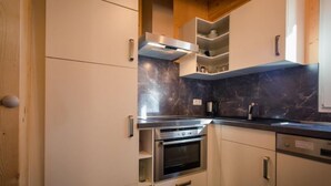Una cocina moderna con armarios blancos, una estufa de acero inoxidable y un salpicadero de mármol.