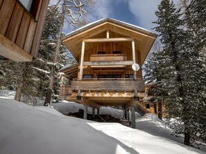 A wooden cabin with a balcony, surrounded by snow-covered trees.