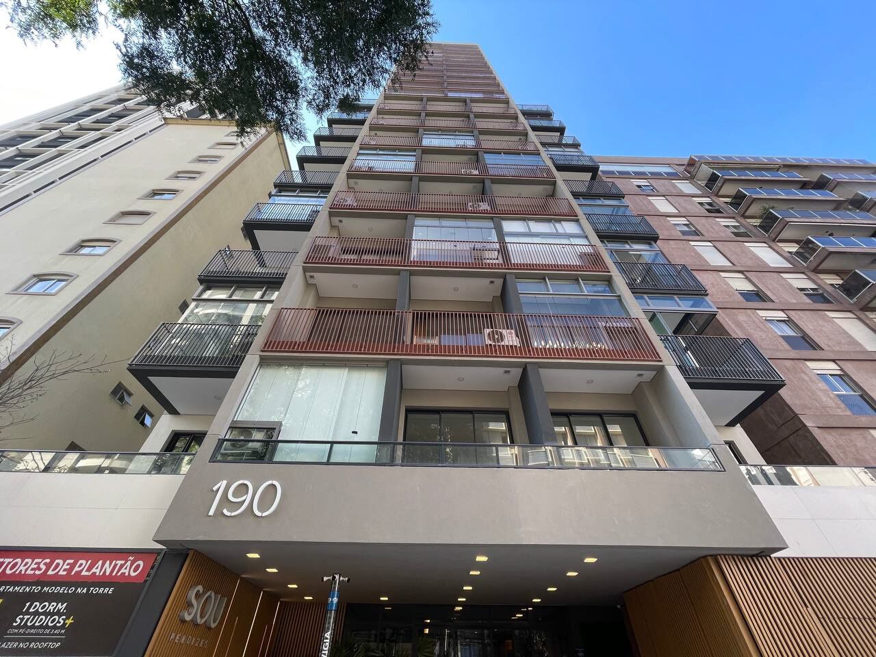 A multi-story building with balconies, a storefront at the ground level, and the number 190 displayed.