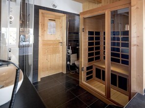 Un baño moderno con puerta de madera, cabina de ducha de vidrio y un armario empotrado de madera.