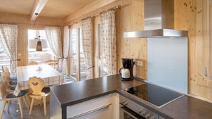 Eine moderne Küche mit Holzschränken, einem eingebauten Backofen und einer Kaffeemaschine auf der Arbeitsplatte.