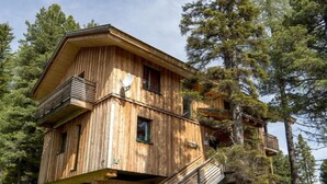 Eine Holzhütte mit Balkon, umgeben von Bäumen.