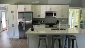Una cocina moderna con armarios blancos, electrodomésticos de acero inoxidable y una isla grande con taburetes de bar.