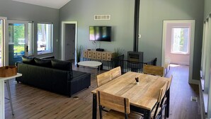 Un amplio salón con techo alto, chimenea, televisor y una mesa de comedor con sillas.