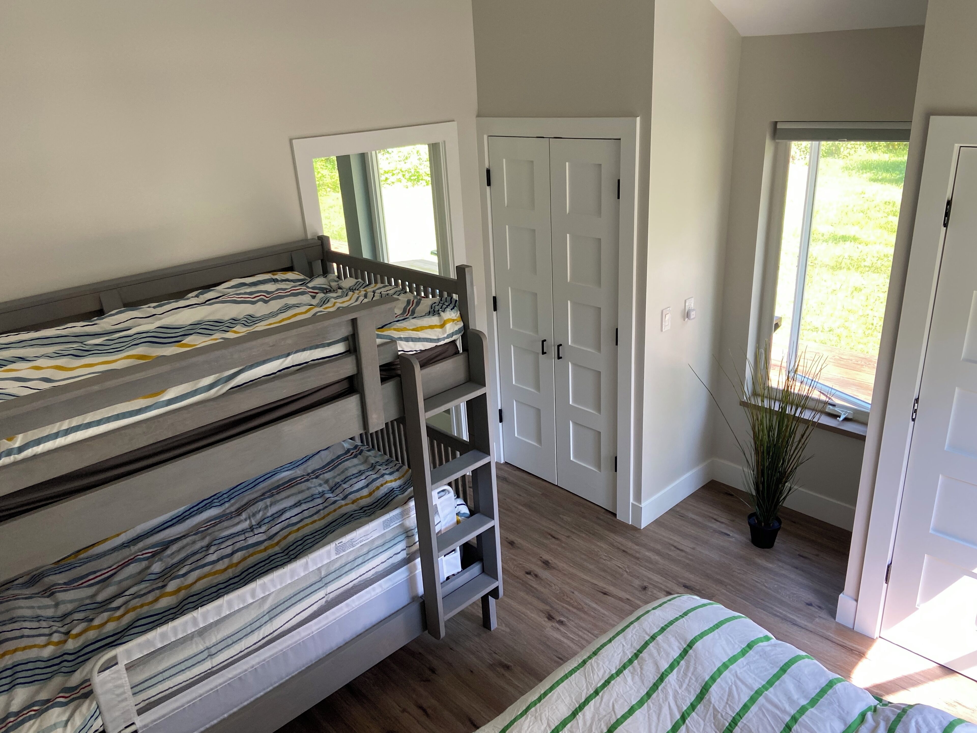 A room with bunk beds, a door, a window, and a potted plant.