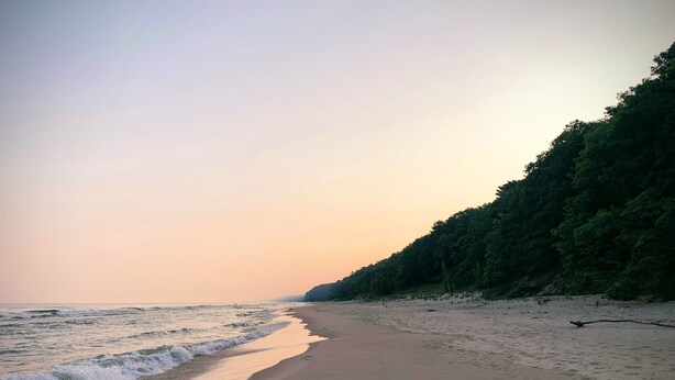Una playa con arena y olas que acarician suavemente la orilla.