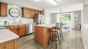 Una cocina moderna con armarios de madera, una isla central, taburetes de bar y vistas a un balcón.
