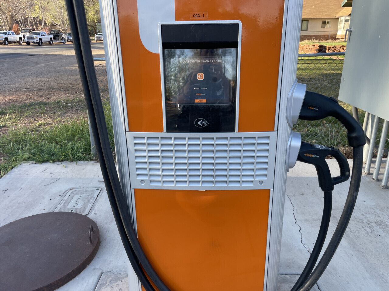 A portable electric vehicle charging station with a digital display, a ventilation grille, and a cable connected to a vehicle.