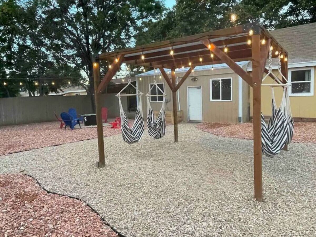 A covered outdoor area with a pergola, string lights, and two hammocks.