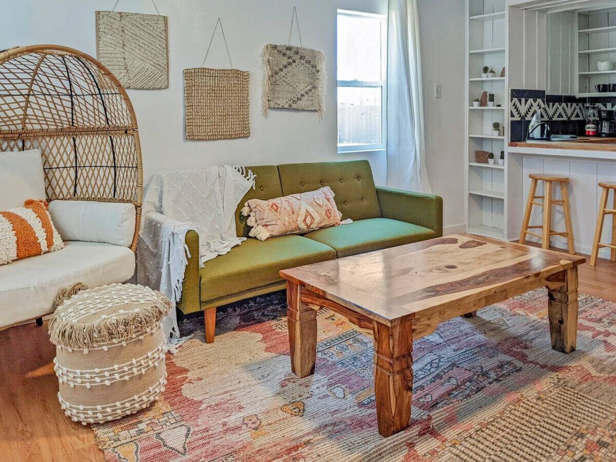 A cozy living room with a green sofa, a wooden coffee table, and a wicker chair.