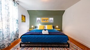 A bedroom with a bed, a headboard, a wall-mounted light fixture, and a window with curtains. - Downtown Kanab • Family & Pet Friendly • Hot Tub (Kanab)