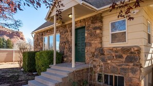 A stone house with a green door, a covered porch, and a small garden area. - Downtown Kanab • Family & Pet Friendly • Hot Tub (Kanab)