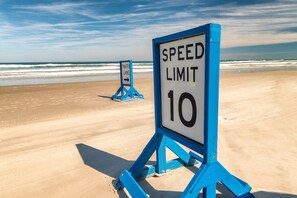 Speed limit sign stands on the sandy beach, overlooking the ocean.