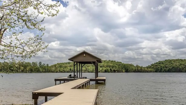 Un muelle de madera que se adentra en un lago, con un pabellón cubierto al final.
