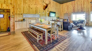 Un interior de madera con comedor, cabeza de ciervo montada y televisor.