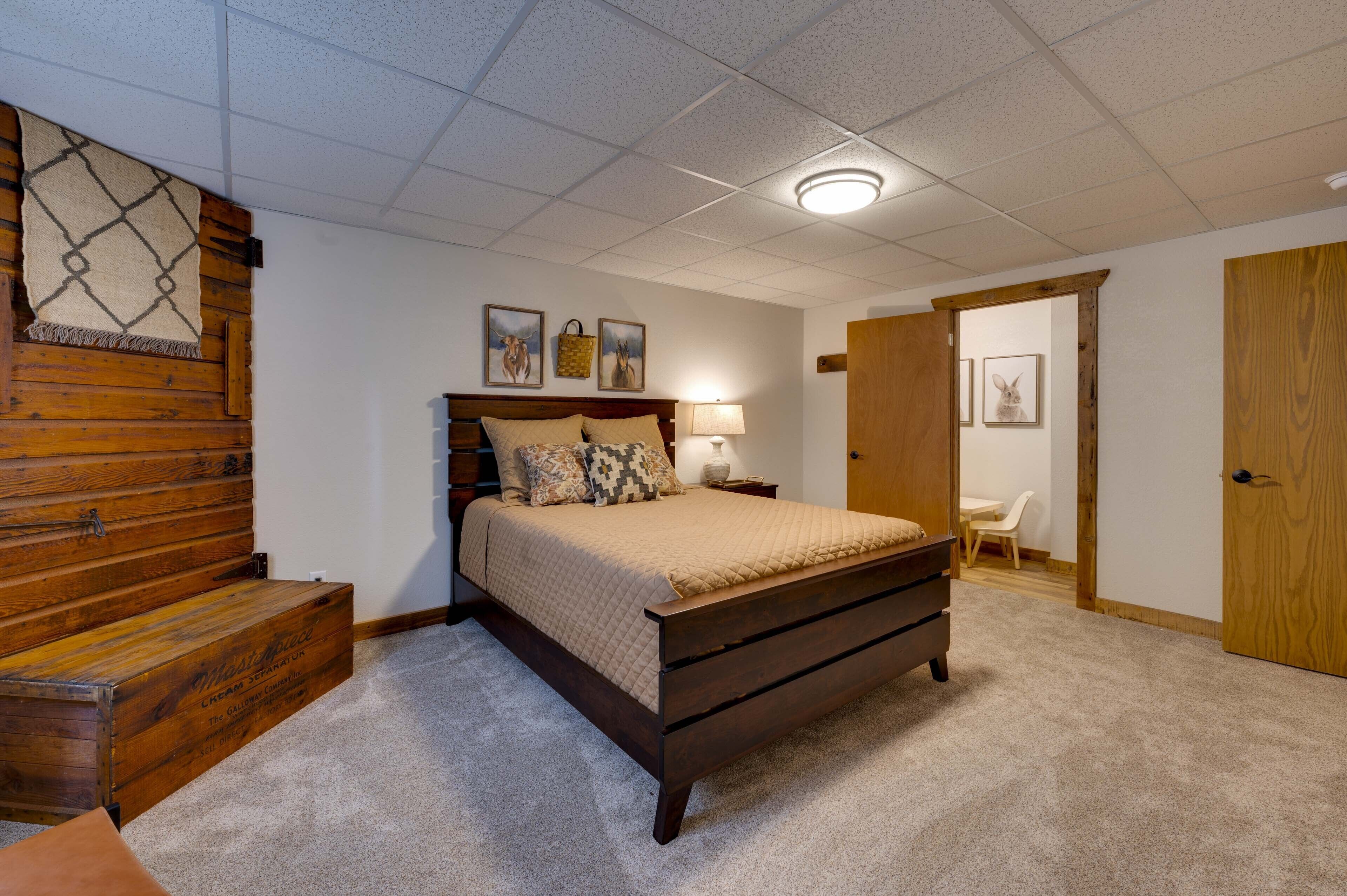 A bedroom with a wooden headboard, a bed with a beige quilt, a nightstand with a lamp, and a wooden dresser.