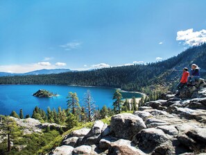 Eine gebirgige Landschaft mit einem See, felsigem Gelände und dichtem Wald.