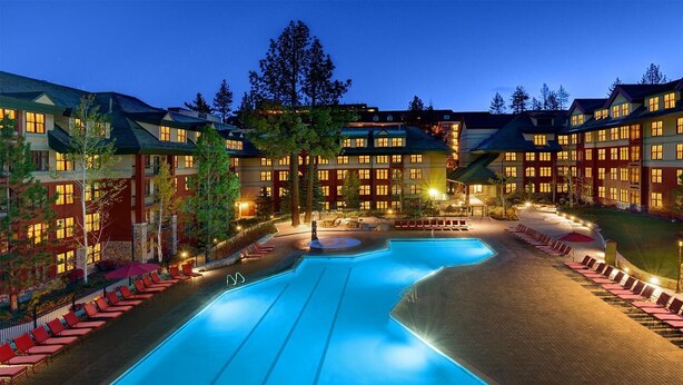 Ein Hotel mit großem Schwimmbad, mehreren Gebäuden und Außenbereichen zum Sitzen.