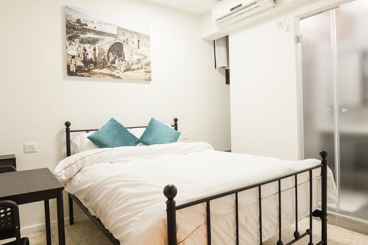 A bedroom with a bed, a desk, and a chair.