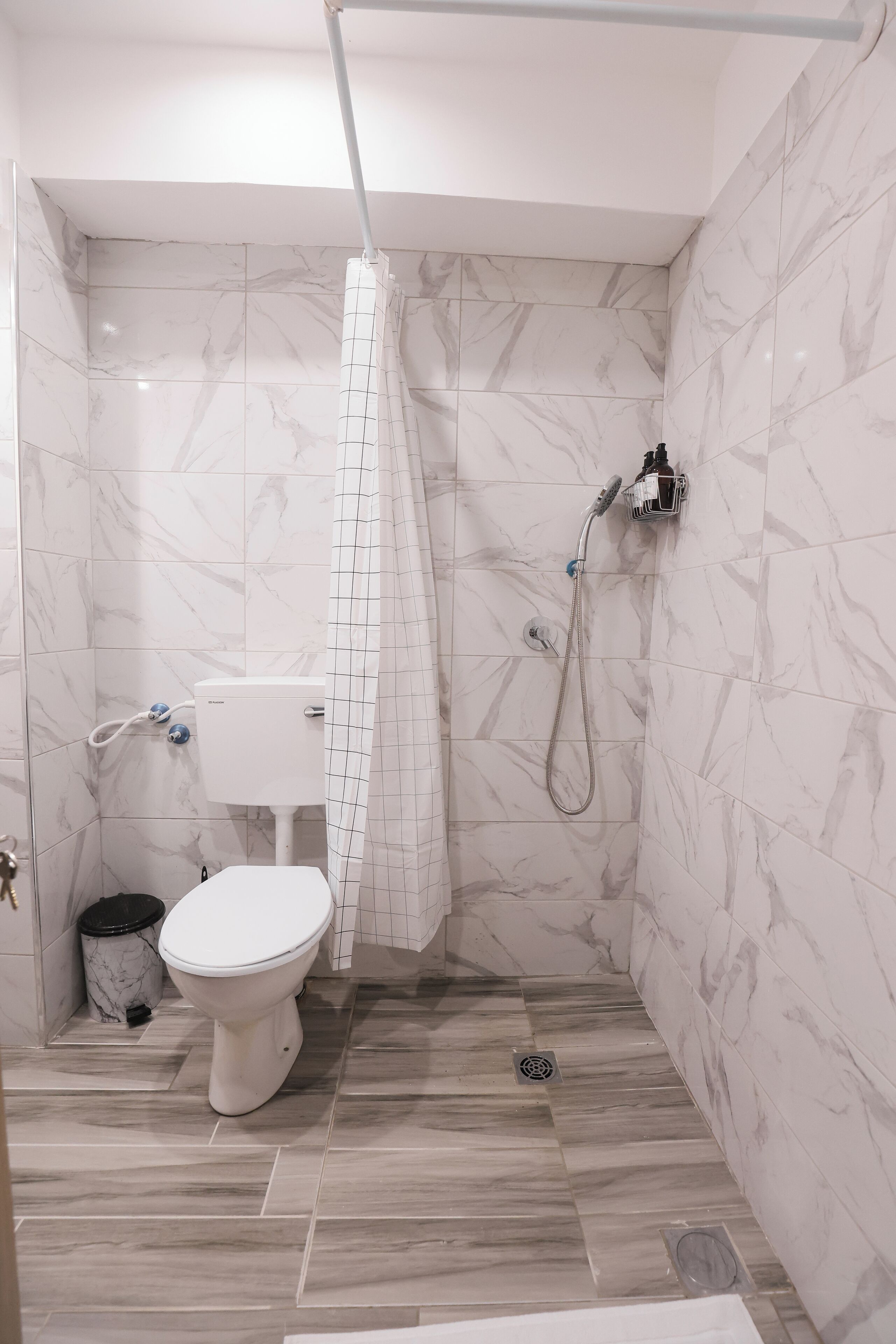 A bathroom with a toilet, shower, and marble tiles.