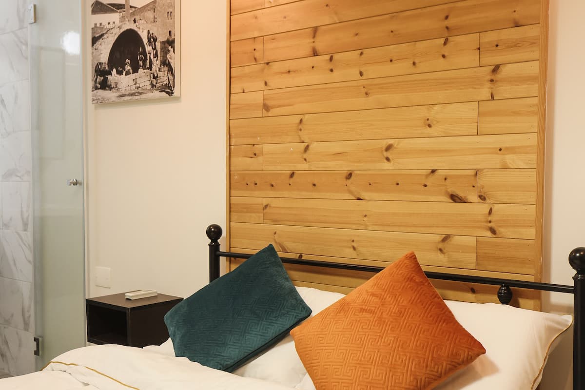 A neatly made bed with a white duvet, two pillows, and a wooden headboard.