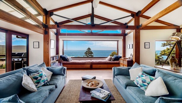 A spacious living room with a large window overlooking the sea, a cozy seating area, and a grill outside. - Atlas - House for all seasons, spa with ocean views and cozy fireplace (KILLCARE)