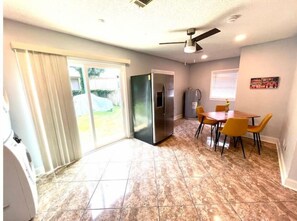 Enjoy meals in the kitchen with a refrigerator and gas water heater, then dine in the adjacent area with a wooden table.