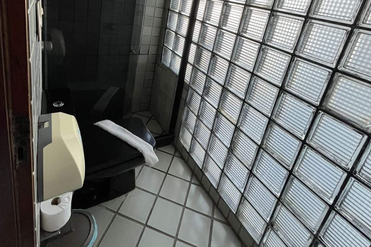 A small, tiled bathroom with a toilet, a sink, and a shower area.