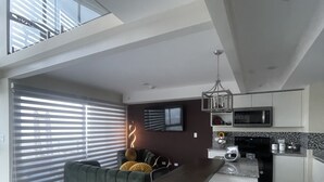 Zona d'estar moderna i oberta amb taula de dinar, sofà i cuina.
